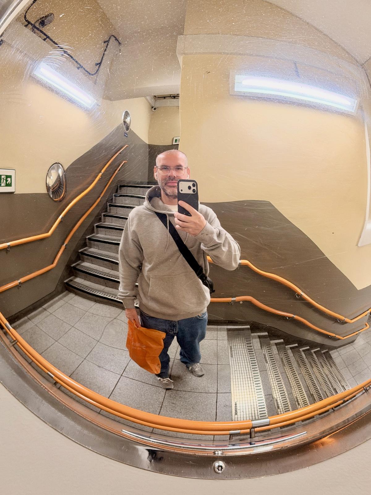 Station mirror selfie of me wearing mid-blue jeans and a grey hoodie