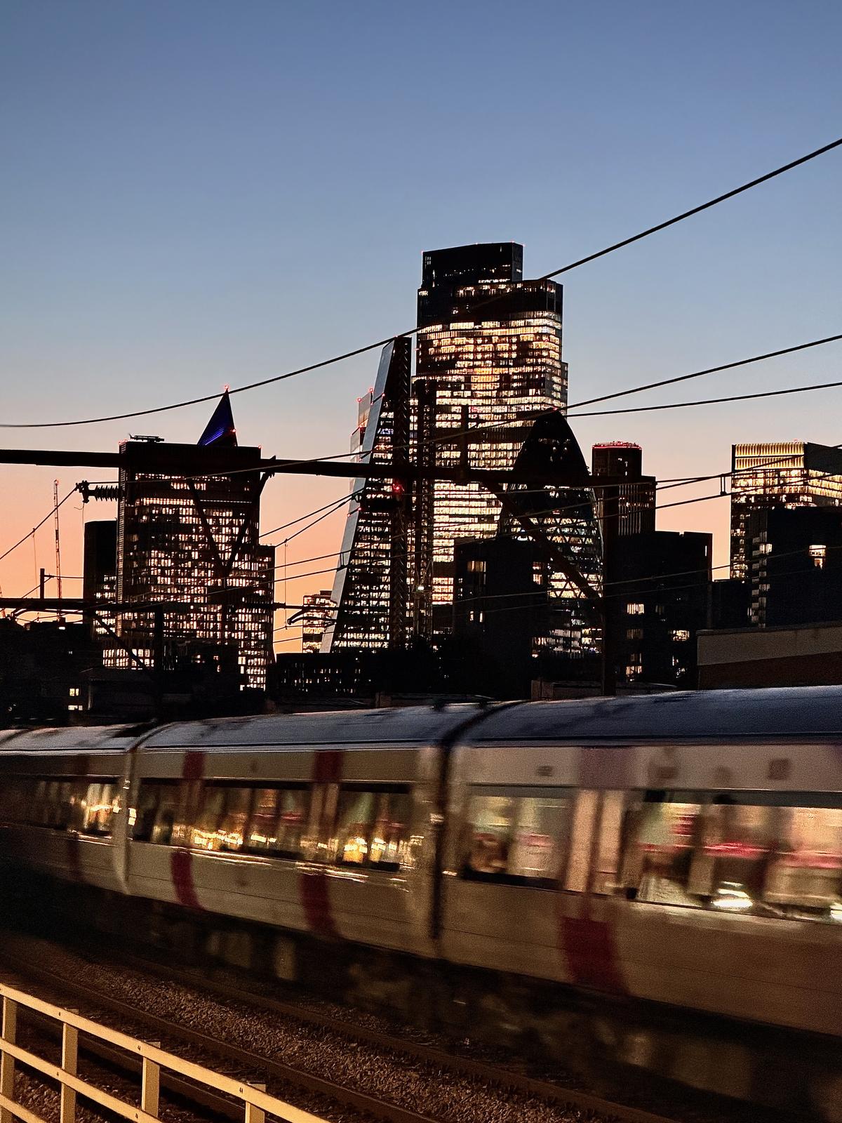 City of London skyline at dusk, with a train passing by in the foreground
