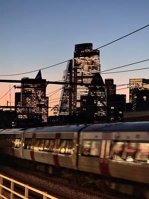 City of London skyline at dusk, with a train passing by in the foreground